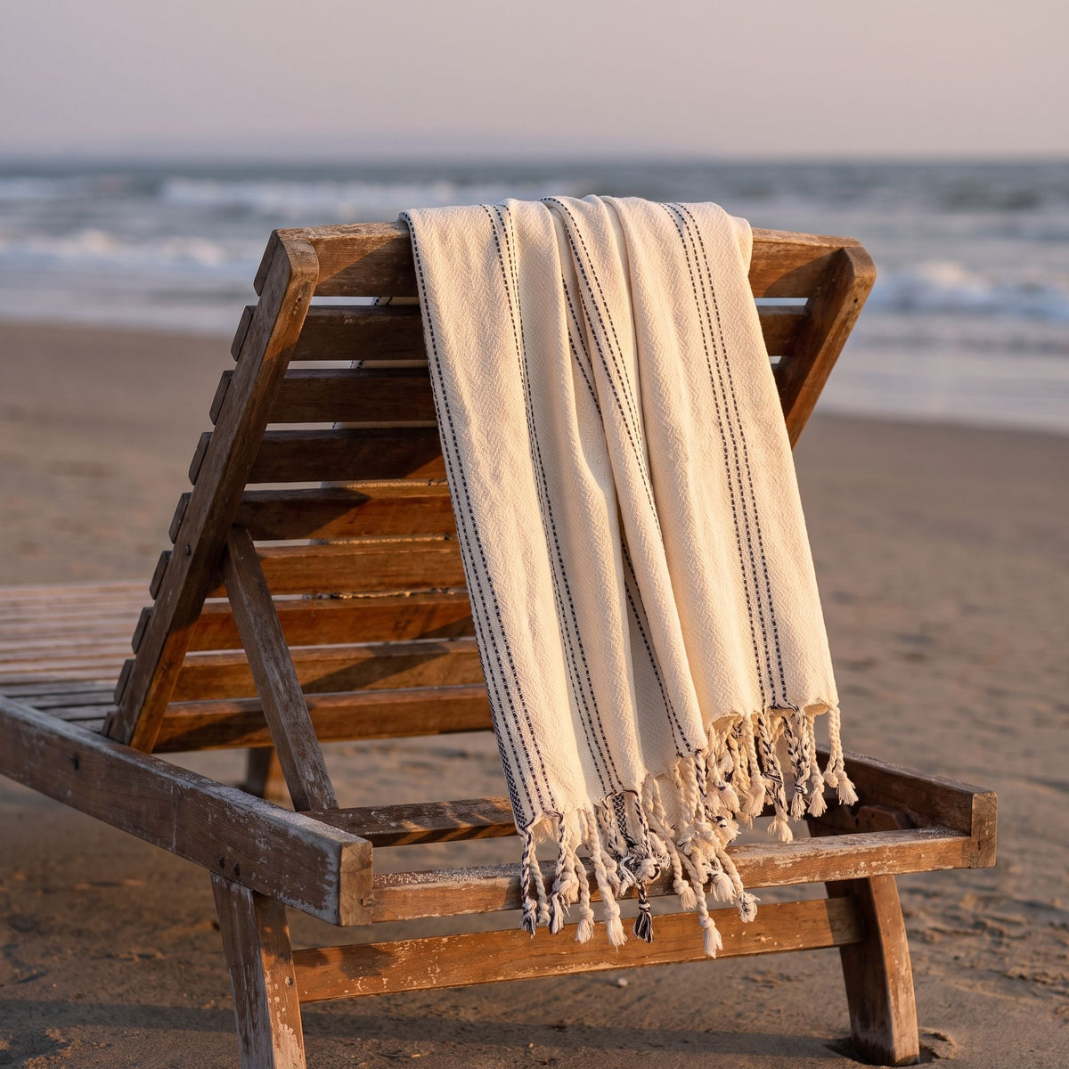 Turkish Towel in Cream with Black, draped over a wooden beach lounger